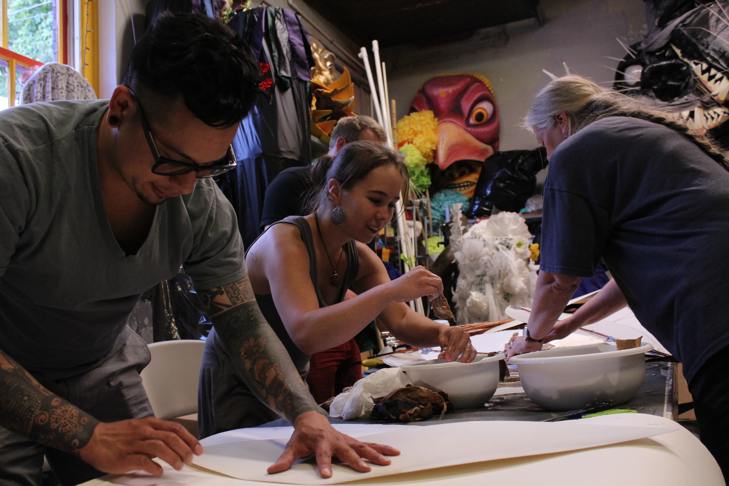  CascadiaNow! volunteers Chris Rivera (left), Morgaine Escudero (middle), and Lisa Bade (right) work on the paper mache leaves that will be used to disguise the Sasquatch from the Sasquatch denier during the Fremont Solstice parade. 