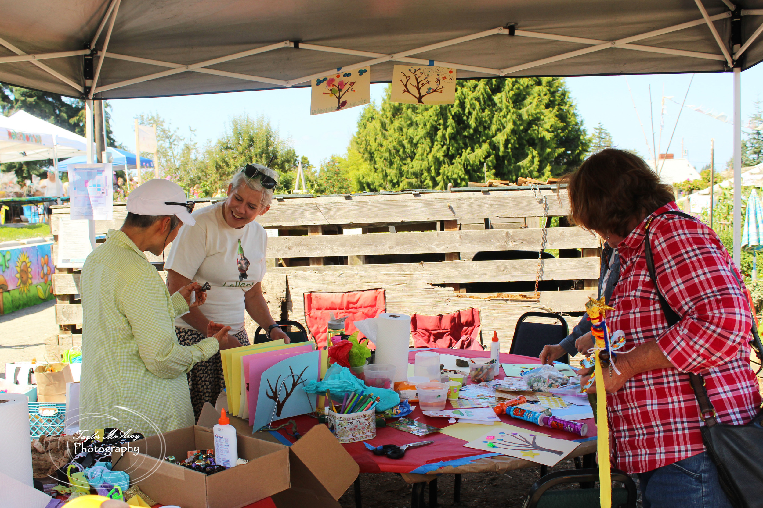  Korinne Kuchling (middle left) helps fellow volunteers set up the kids booth promoting hands on arts and crafts. Korinne and her husband have been volunteering at the P-Patch for about 7 years.&nbsp; 