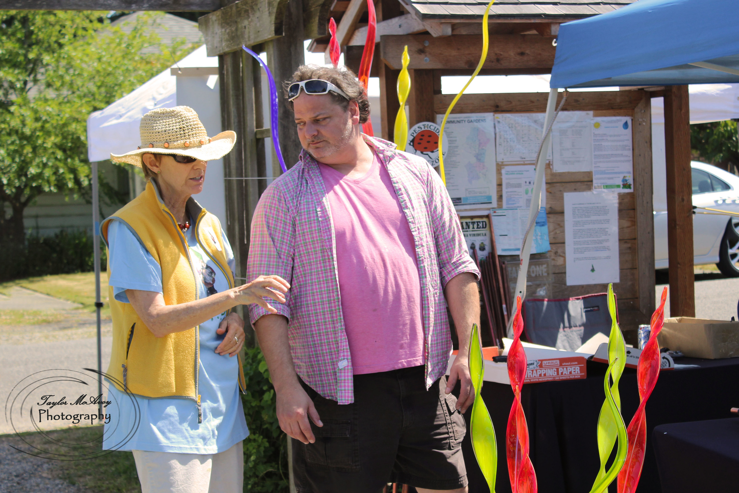  Glass artist Dayne Lopez chats with a community member about his art pieces.&nbsp; 