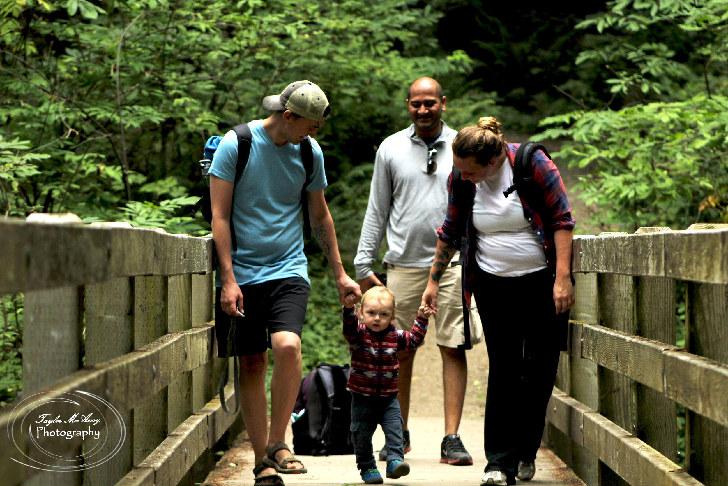  (From left to right) Andrew Schlosser, his son Atlas, AAditya Juwad, and Tephra Schlosser enjoy the view from the bridge of a small waterfall along the trail. Atlas enjoys the break from being carried to stretch his legs.&nbsp; 