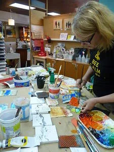 Local artist and owner of ARTspot Tracy Felix demonstrates painting techniques on 5x5 inch canvases in her shop’s studio. She hosted a 25 Day Creativity Challenge for other artists, challenging them to create 25 5x5 inch original pieces in 25 days. Photo by: Laura Daniali