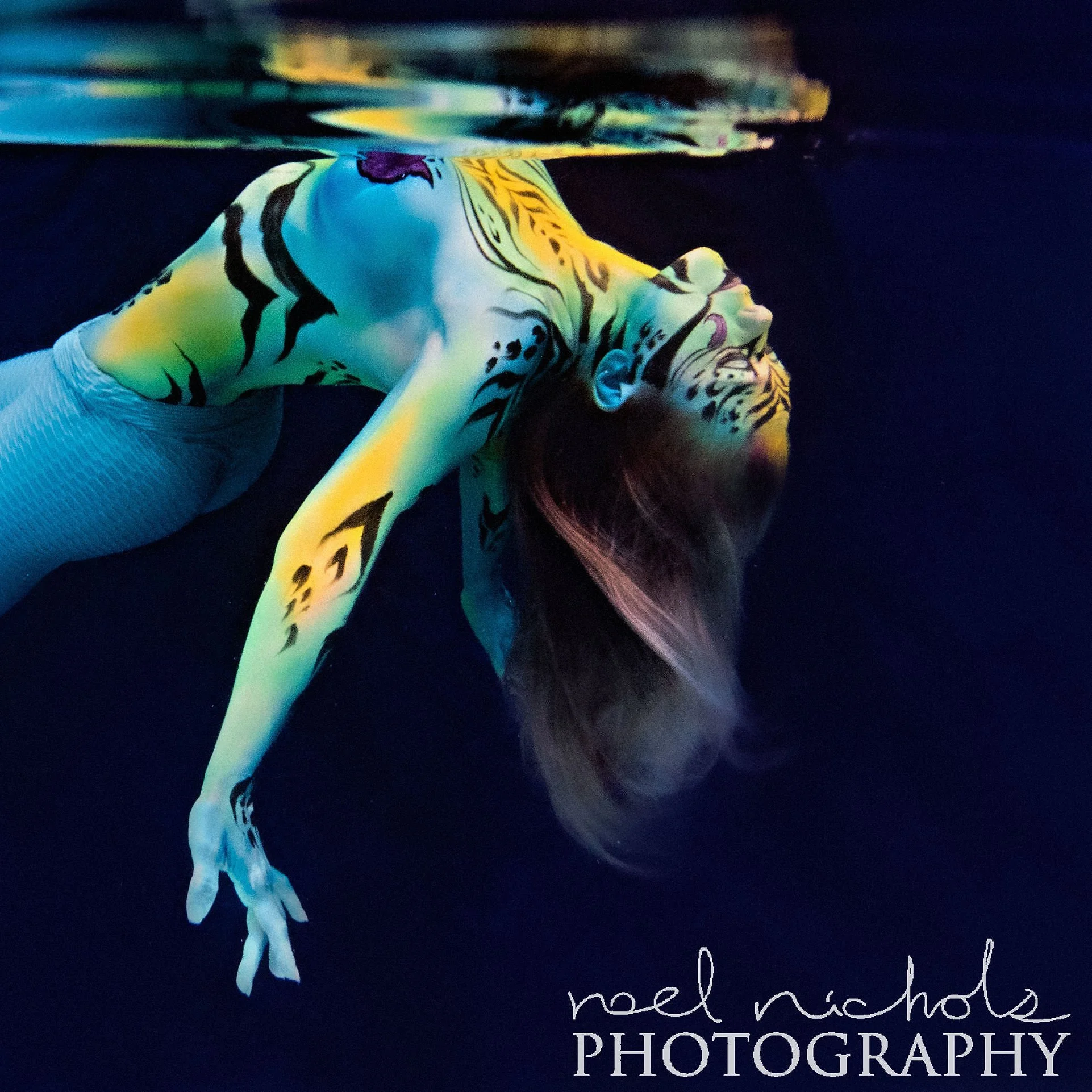 photo of a woman with painted yellow and blue stripes underwater