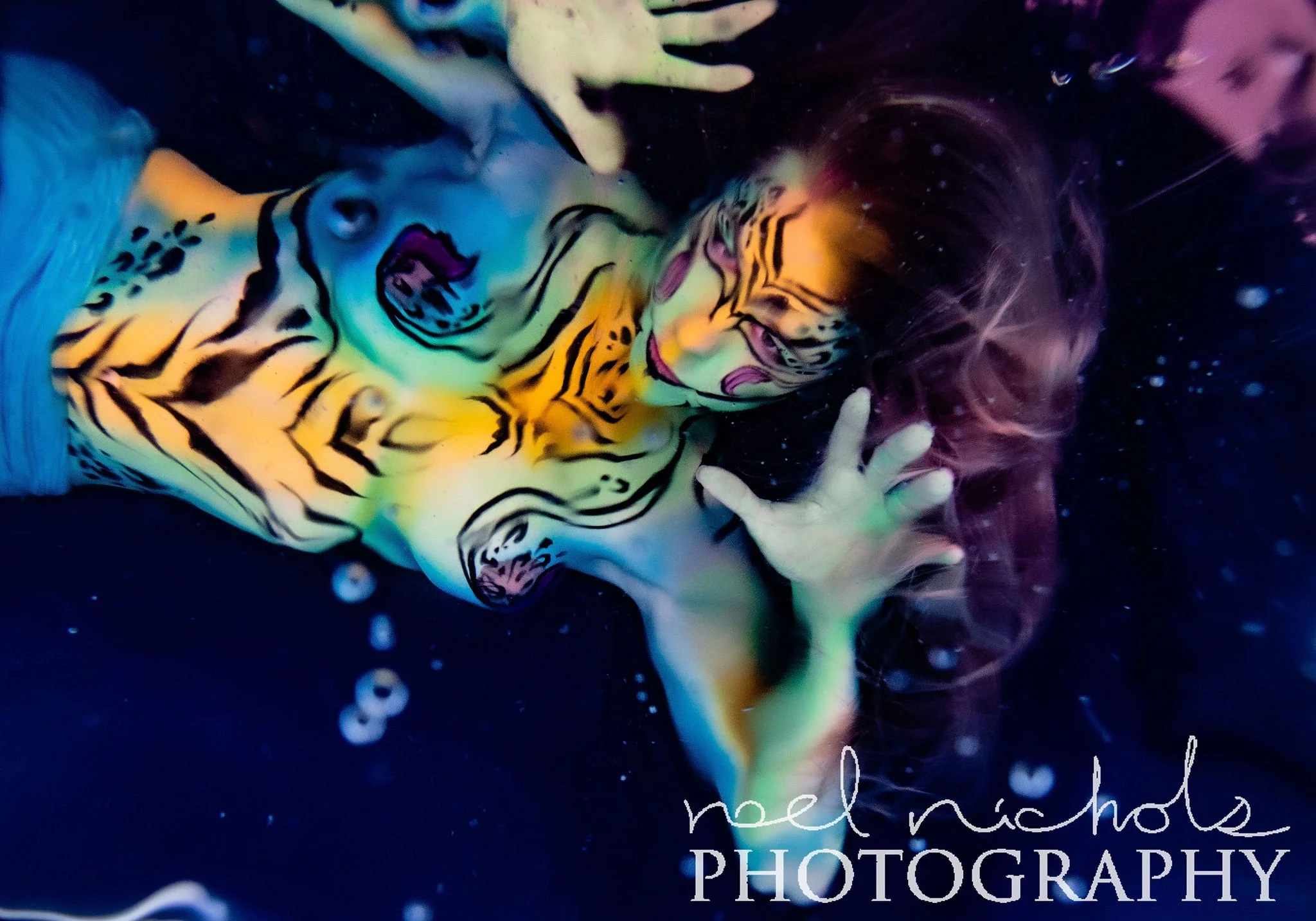 photo of a woman with painted yellow and blue stripes underwater