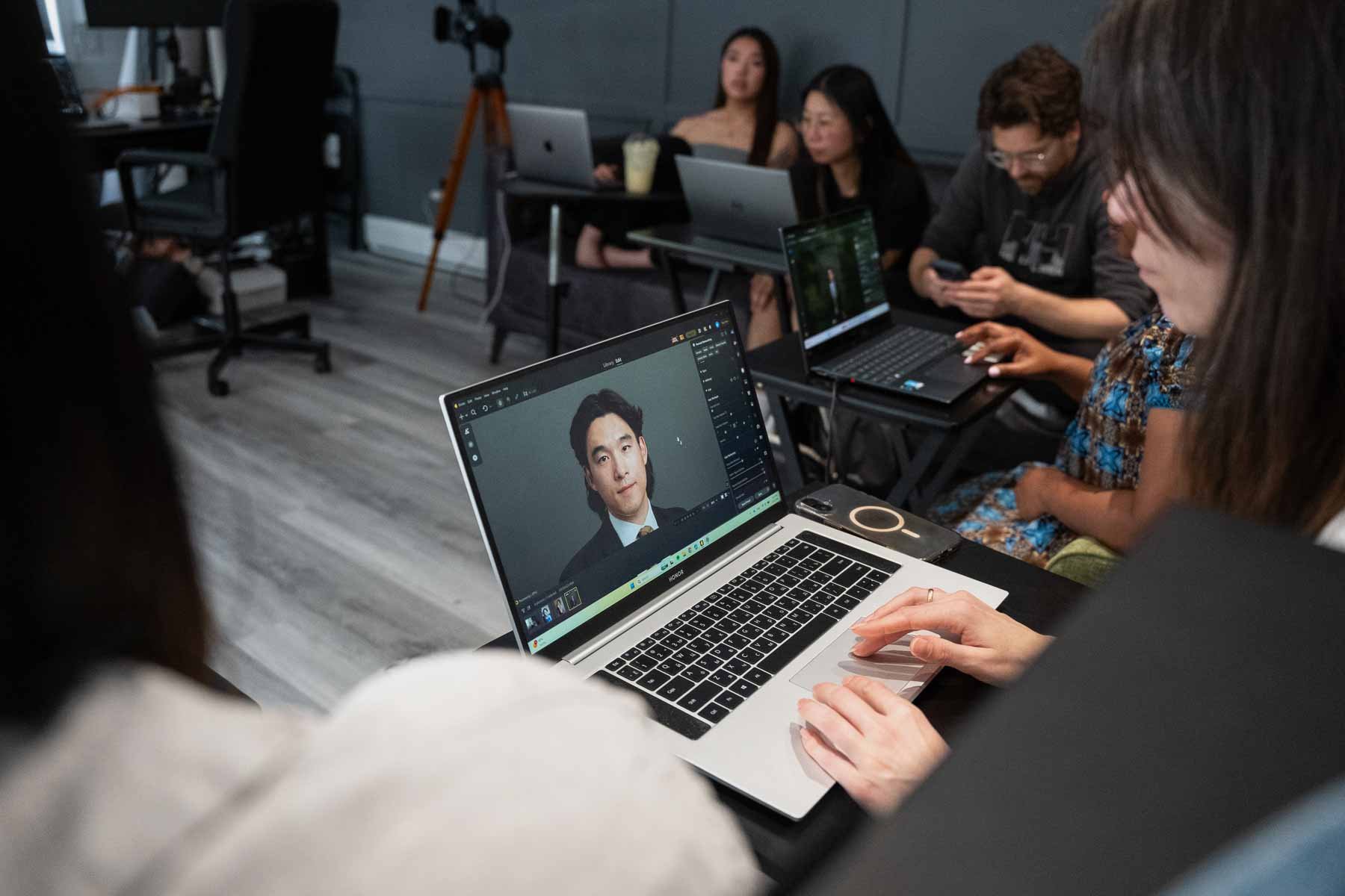 Students learning photo editing and content creation on laptops during a photography and video production class in Winnipeg.