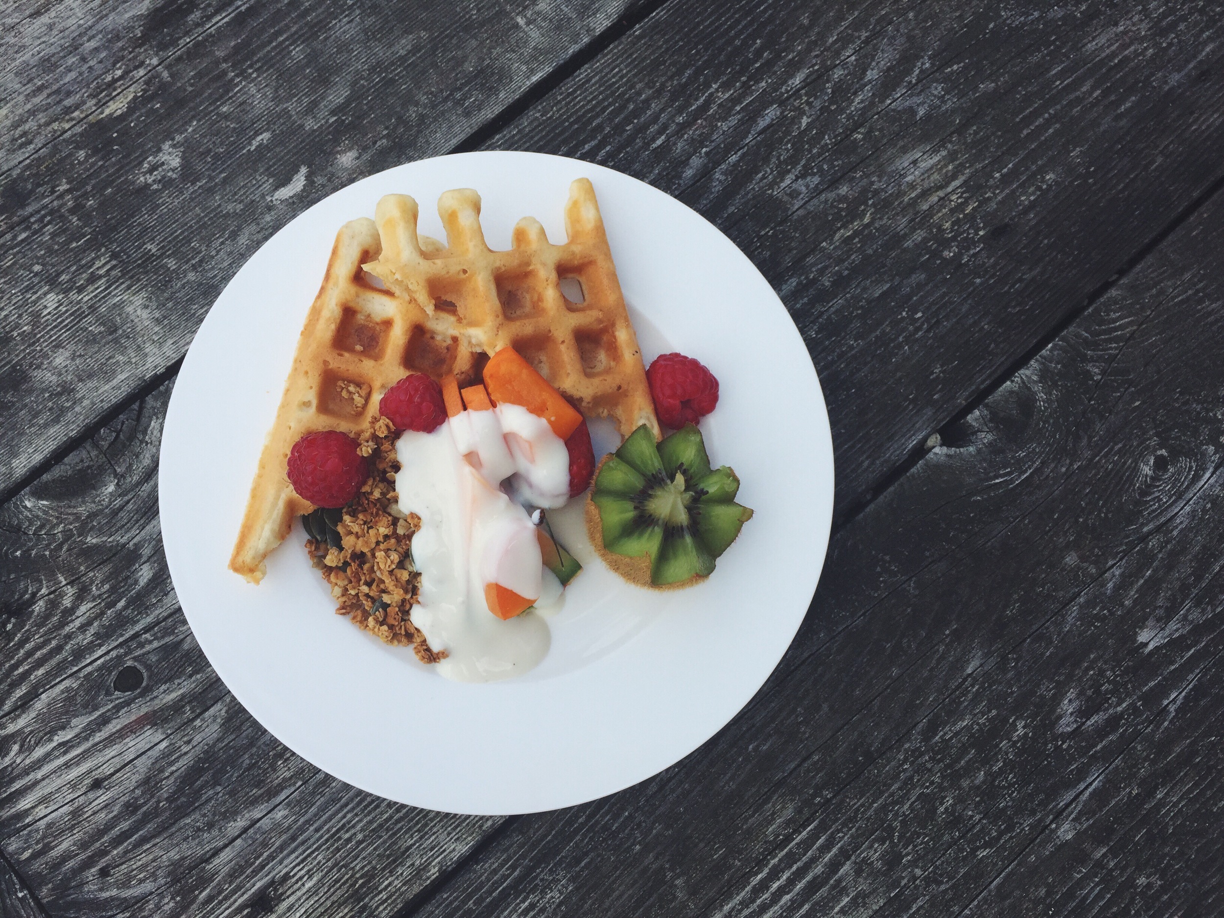 Homemade oat waffles with homemade maple syrup granola, chopped fruit and almond yoghurt