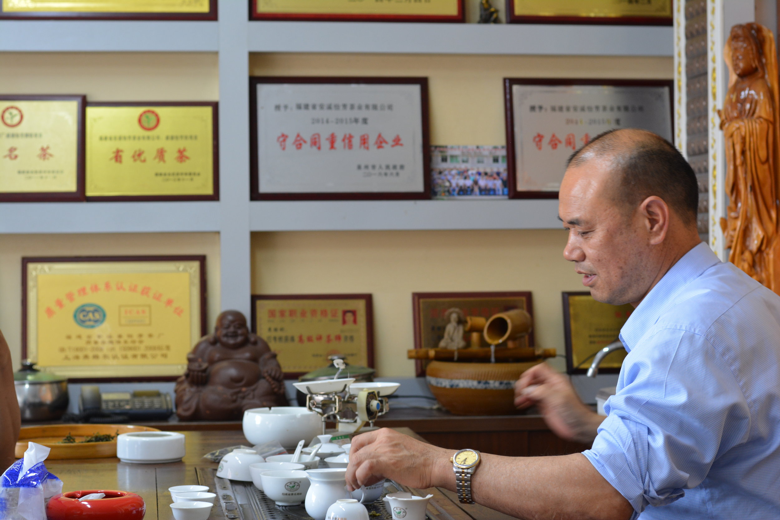 I had the pleasure of meeting Mr. Lee and his family. The shelves in the background showcase the numerous accolades he receives year after year for the award-winning Iron Goddess of Mercy, Tie Guan Yin, that he produces for us.
