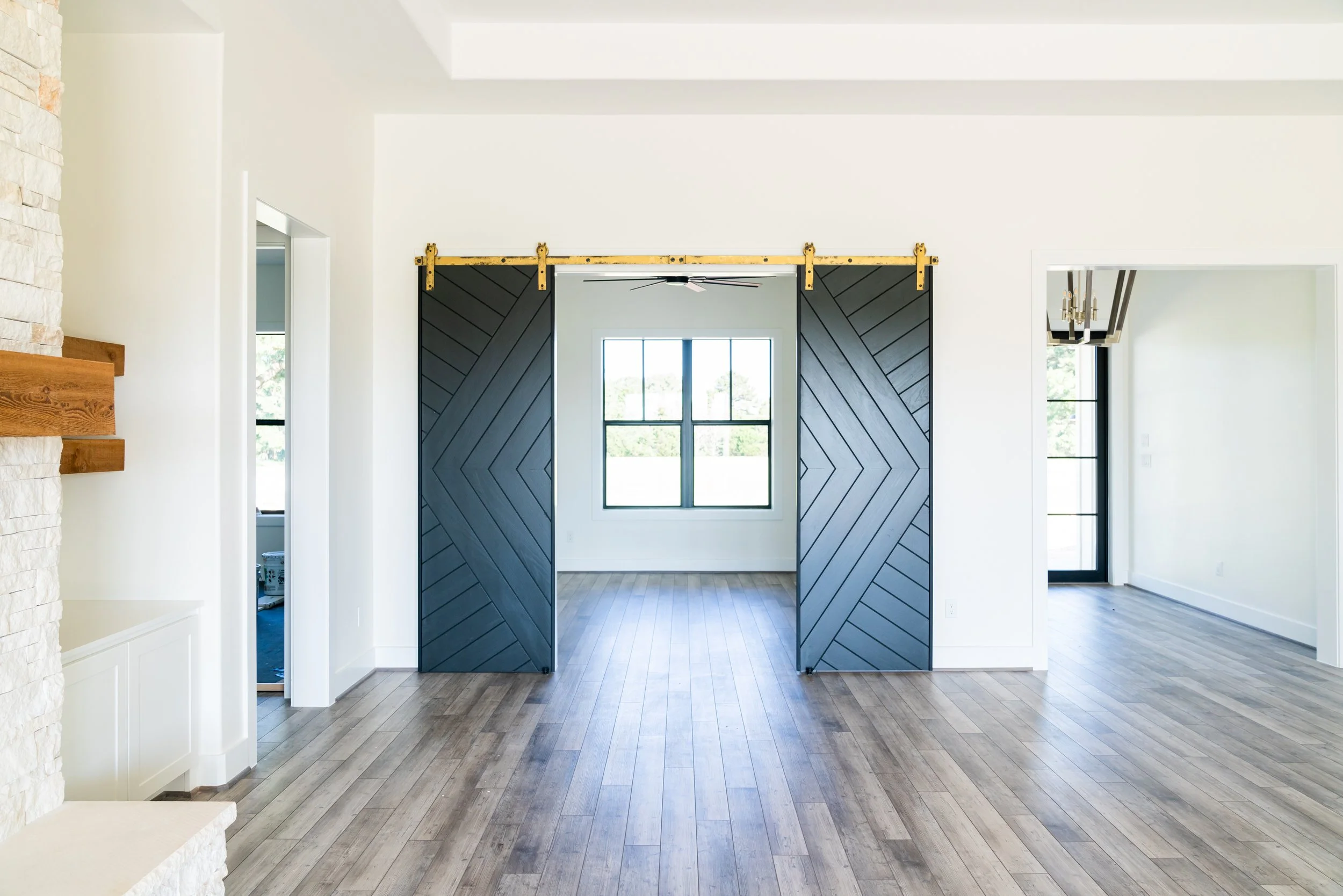 Interior of a modern house with hardwood floors, white walls, and sliding barn doors painted black.