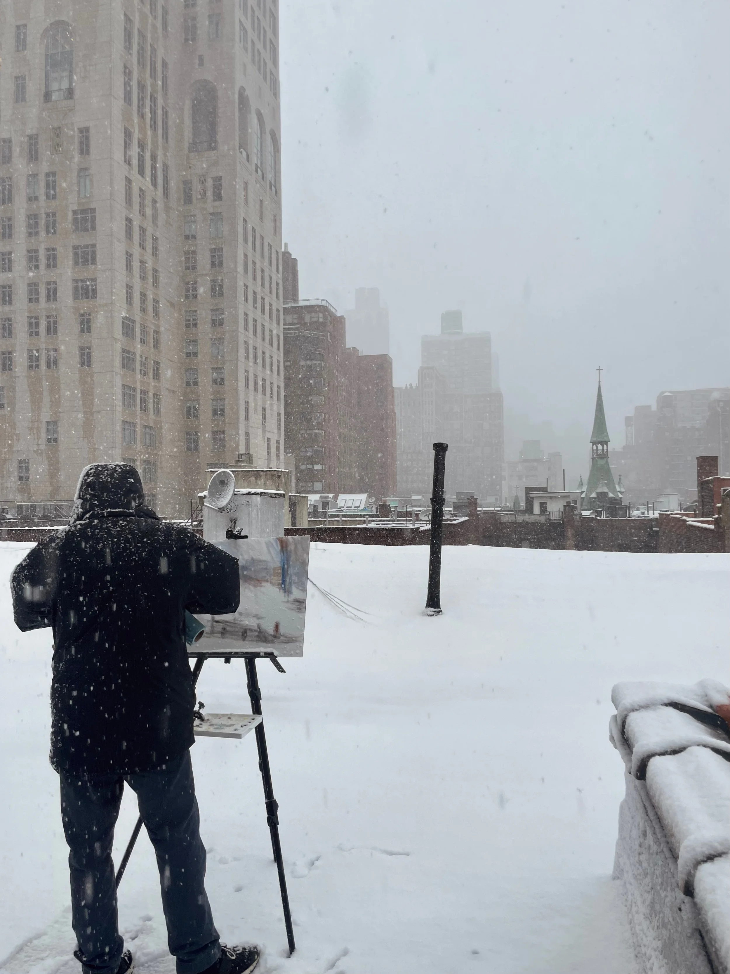 Artist painting en plein air on a snowy rooftop in Manhattan