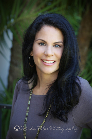 Makeup is natural and not overdone, solid purple sweater is a great compliment to her dark hair and blue eyes, jewelry is subtle but shows her style, green outdoor settings offsets her coloring beautifully!