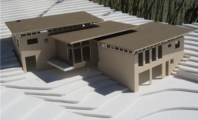 Architectural model for a home designed using modularity principals and constructed from rammed earth Watershed Block . The dimensions of the structures were designed in multiples of the dimensions of the blocks to avoid waste from cutting blocks. The structure was designed with two primary structures connected by adjoining roofs to create a third living space between.