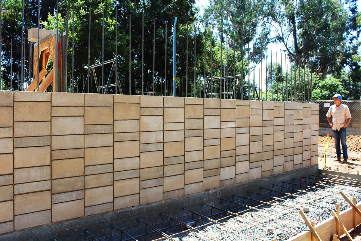 David Easton inspecting the block work in progress. One of the drawbacks to stacked bond rather than running bond is that vertical reinforcing bars are required in all cells prior to grouting with high strength low carbon concrete.
