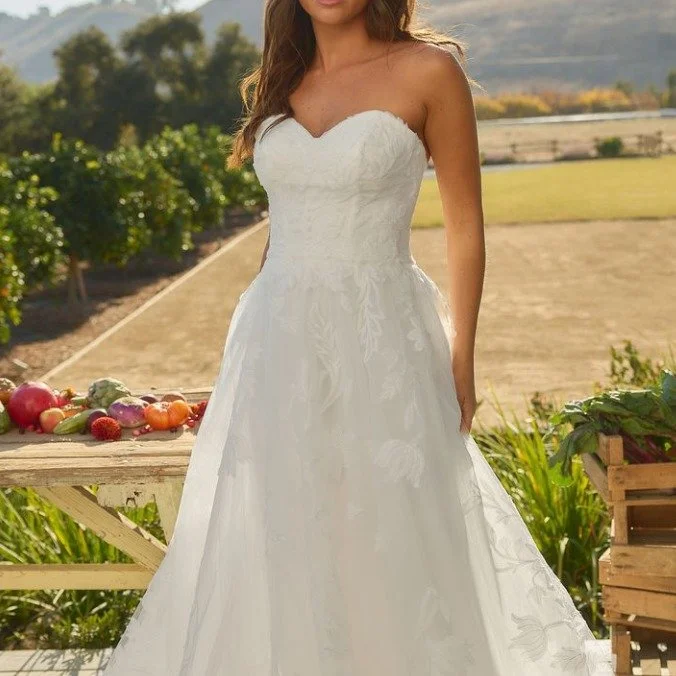 New Arrival!
Dorothy is for the bride who loves romance with a touch of nostalgia. This strapless A-line gown features a sweetheart neckline, effortlessly flowing into layers of soft tulle and floral lace appliqués. The gown’s crinoline