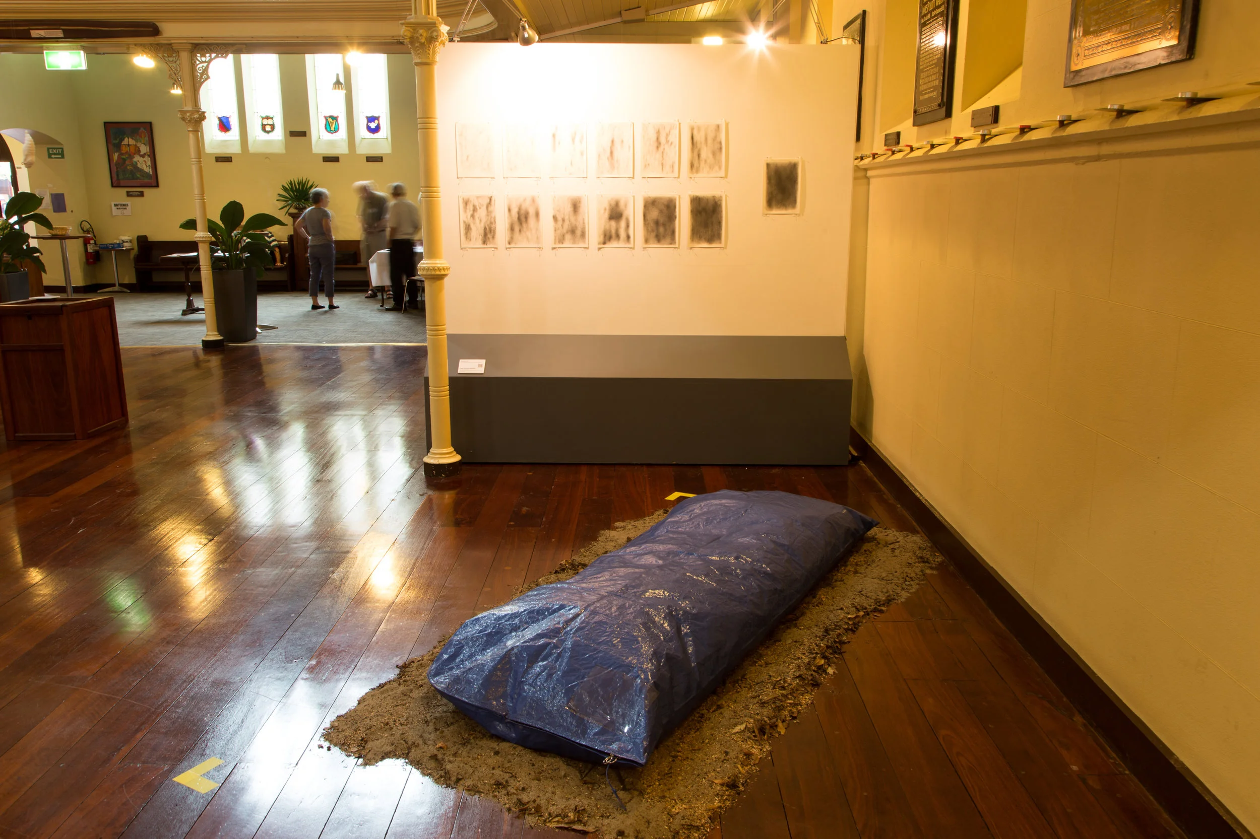 Station 13: Jesus' Body is Taken Down from the Cross Kate Koivisto Wheeler Underworld 016, Pencil, charcoal, paper, body bag, leaves and earth Size variable