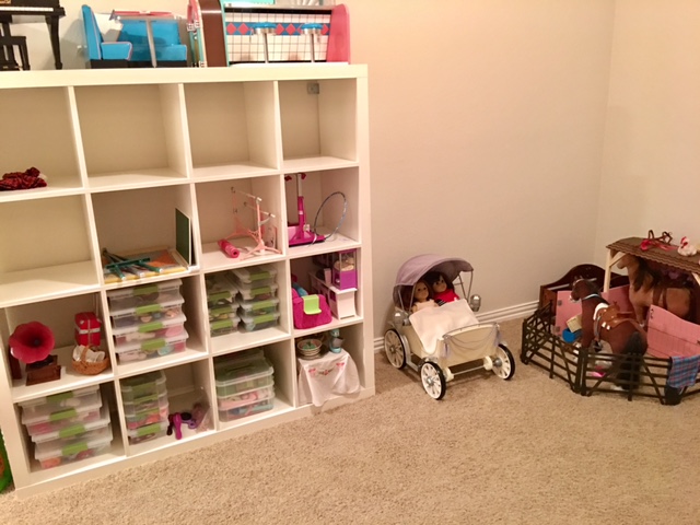 Ikea Expedit series is the holy grail of doll room storage! Each of the historical dolls have their own plastic container with their shoes and accessories- like headbands, purses, jewelry, things like that. There are also large plastic containers for all of the Truly Me shoes, Bitty Baby shoes, etc. This is also where we keep furniture pieces that she can swap in and out of her AG doll house. To the right is the carriage (the horse can attach to it) and the AG stable combined with the Our Generation horse barn 