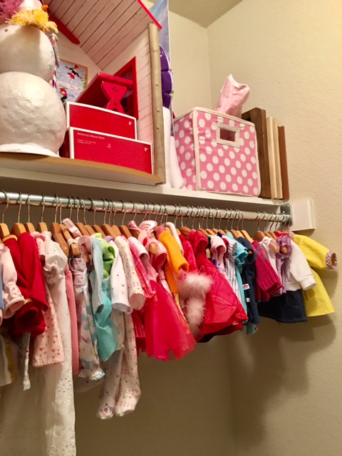 We keep all of the Bitty Clothes here in the nursery. You can get a better look at the wooden doll hangers here in this picture. SUPER TIP: Some of the more delicate, silk doll dresses like to slip off the hangers. To keep this from happening, I use the itty bitty rubber hair bands . I wrap them around the ends of the hanger arms and it creates a little grip to keep them from slipping off! 