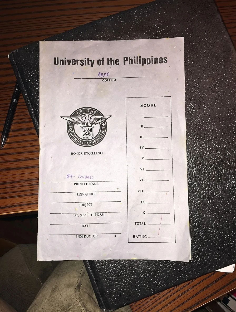 A University of the Philippines blue book exam booklet from the College of Social Sciences and Philosophy, marked with a grade of 1