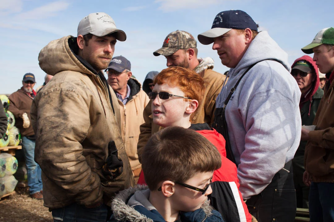 A group of men listen to the auctioneer during an outdoor consignment auction in Holt County, Nebraska. February 2014