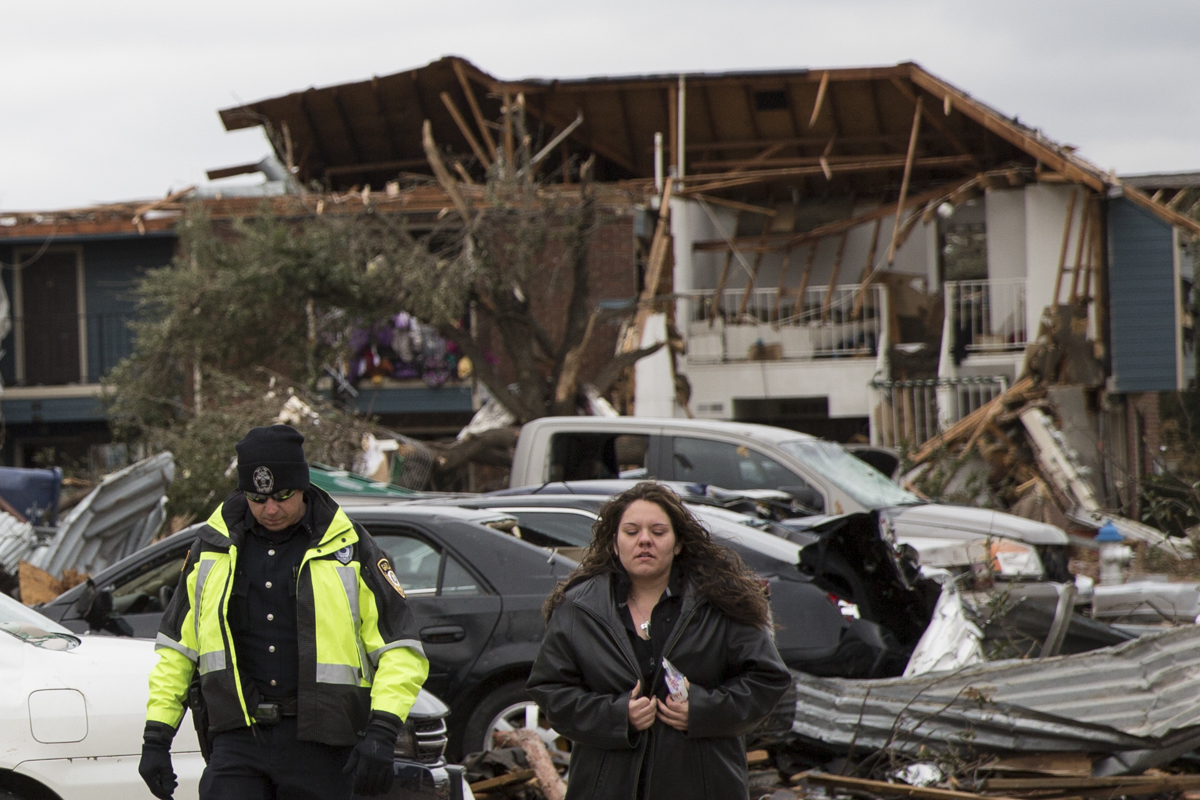  A young woman is escorted from her apartment complex in Garland, Texas, following a tornado the destroyed much of the complex. 
