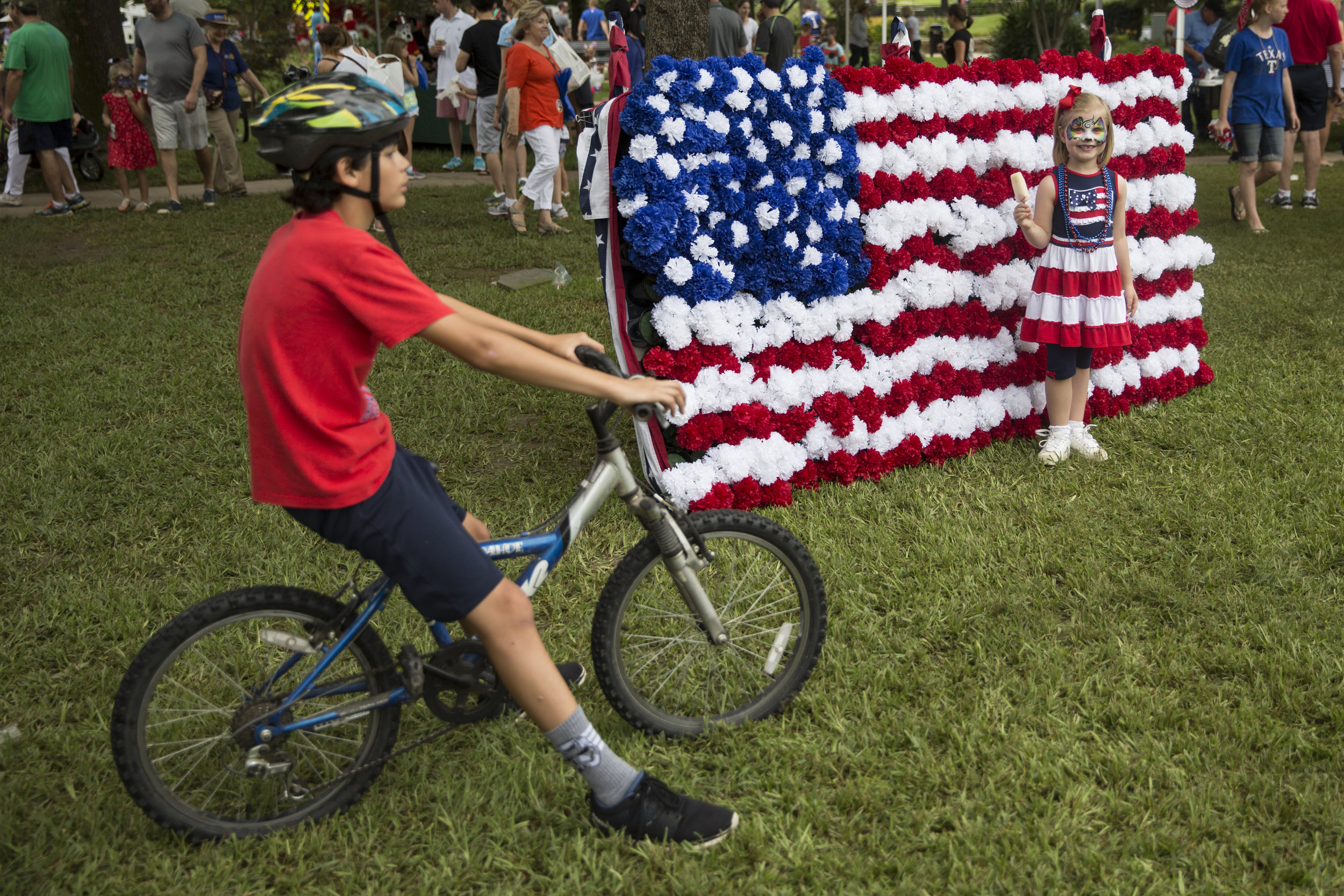  A young girl stands for a portrait in front of an American flag backdrop during an Independence Day celebration in Highland Park, Texas. 