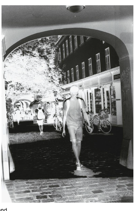 a negative of a person walking through a street underpass or bridge