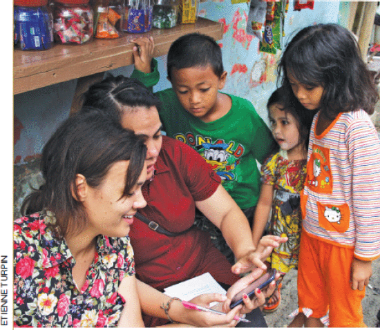 PetaJakarta.org team survey damage along the Ciliwung River using GeoSocial Rapid Assessment Survey Platform (#GRASP) via Twitter, as neighborhood children look on.