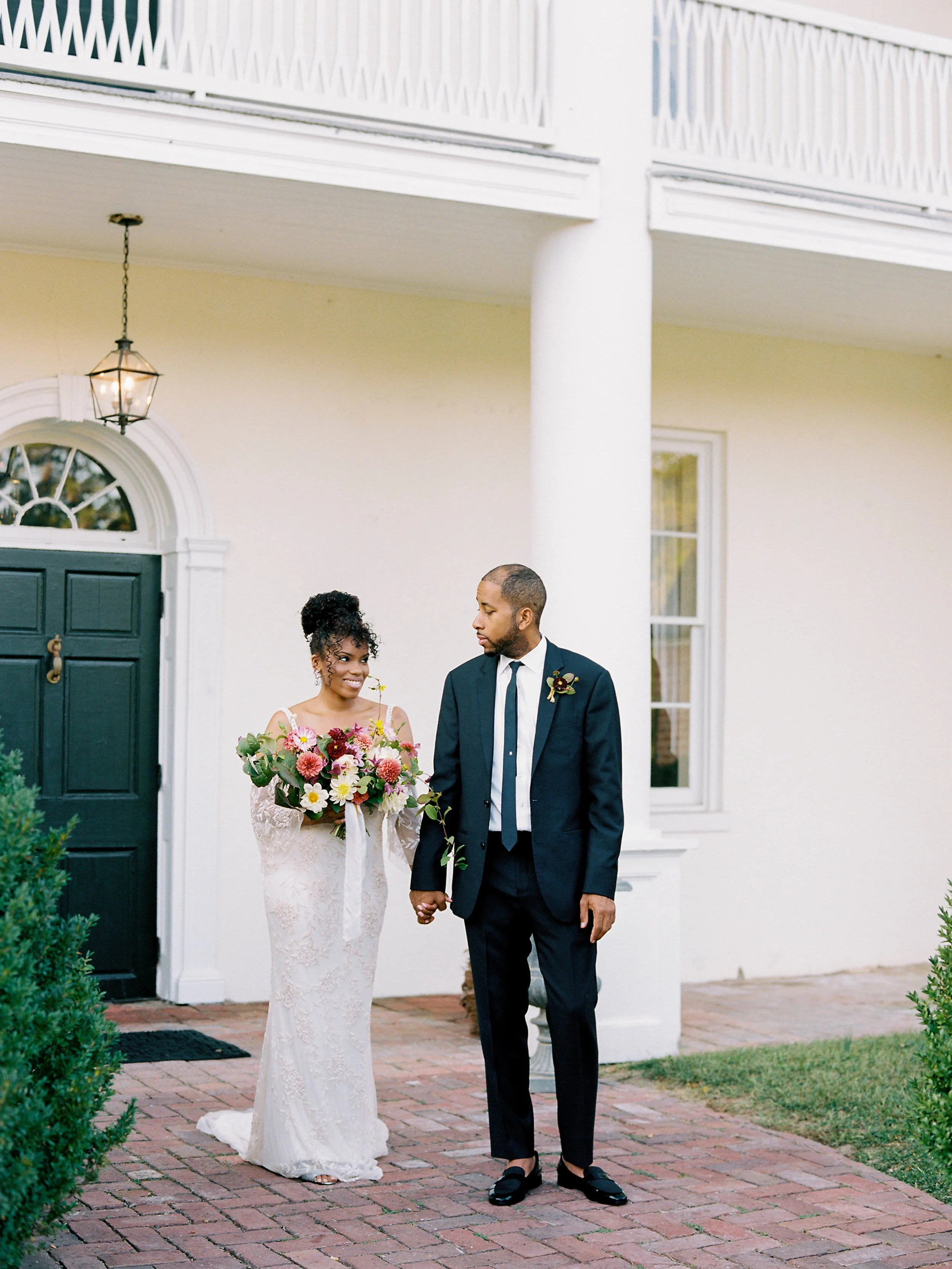 Bride and groom outside a white estate venue with columns