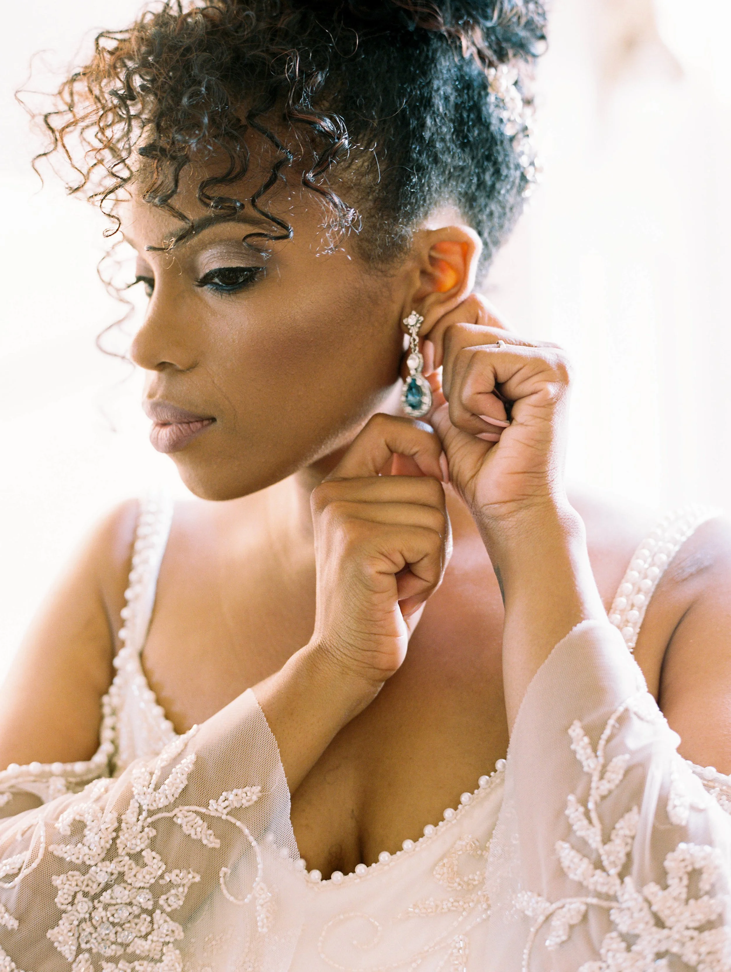 Bride fastening an earring, close-up of soft glam eye makeup