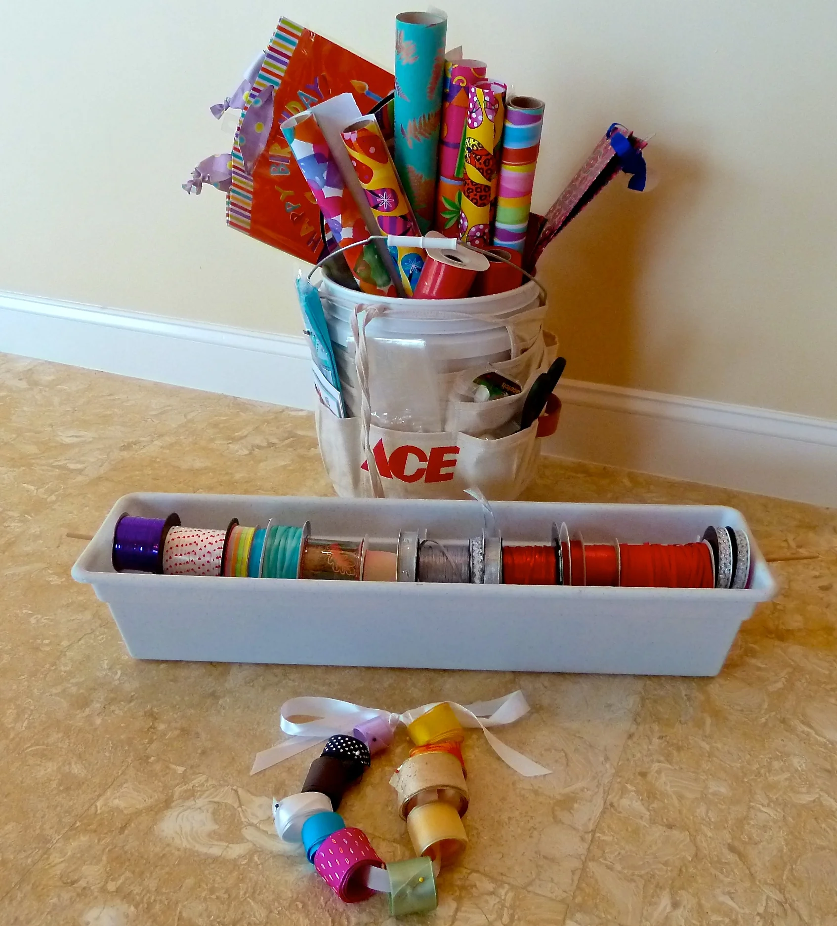 Tools required-large paint bucket, tool pouch tied around the bucket, plastic window box with a long dowel to hold the rolls of ribbon. If you have leftover ribbon just roll and pin them around a chord of ribbon. 
