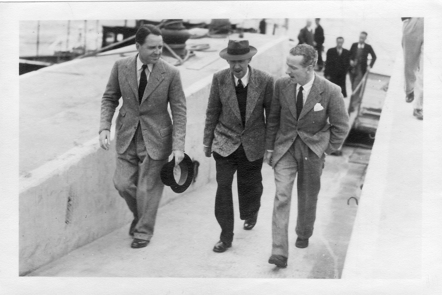 Colonial Secretary MacDougall (right) returns from a trip, greeted by Max and DCA Albert Moss, January 1947