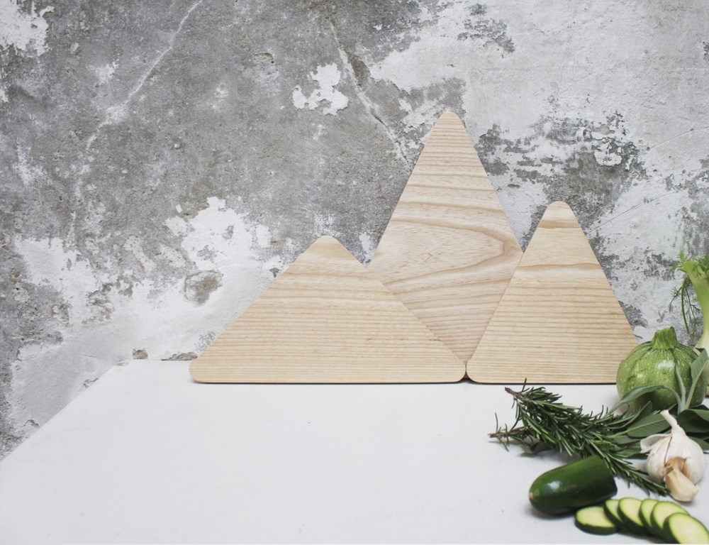 The Mountains is a set of triangular chopping boards designed to resemble a mountain range when stacked together. The Mountains are made from solid ash, and contains of three designs, each an isosceles triangle, but with different heights and widths. The combination possibilities are many, so you can vary and create your very own mountain horizon. Designed by Runa Klock for Trefjøla
