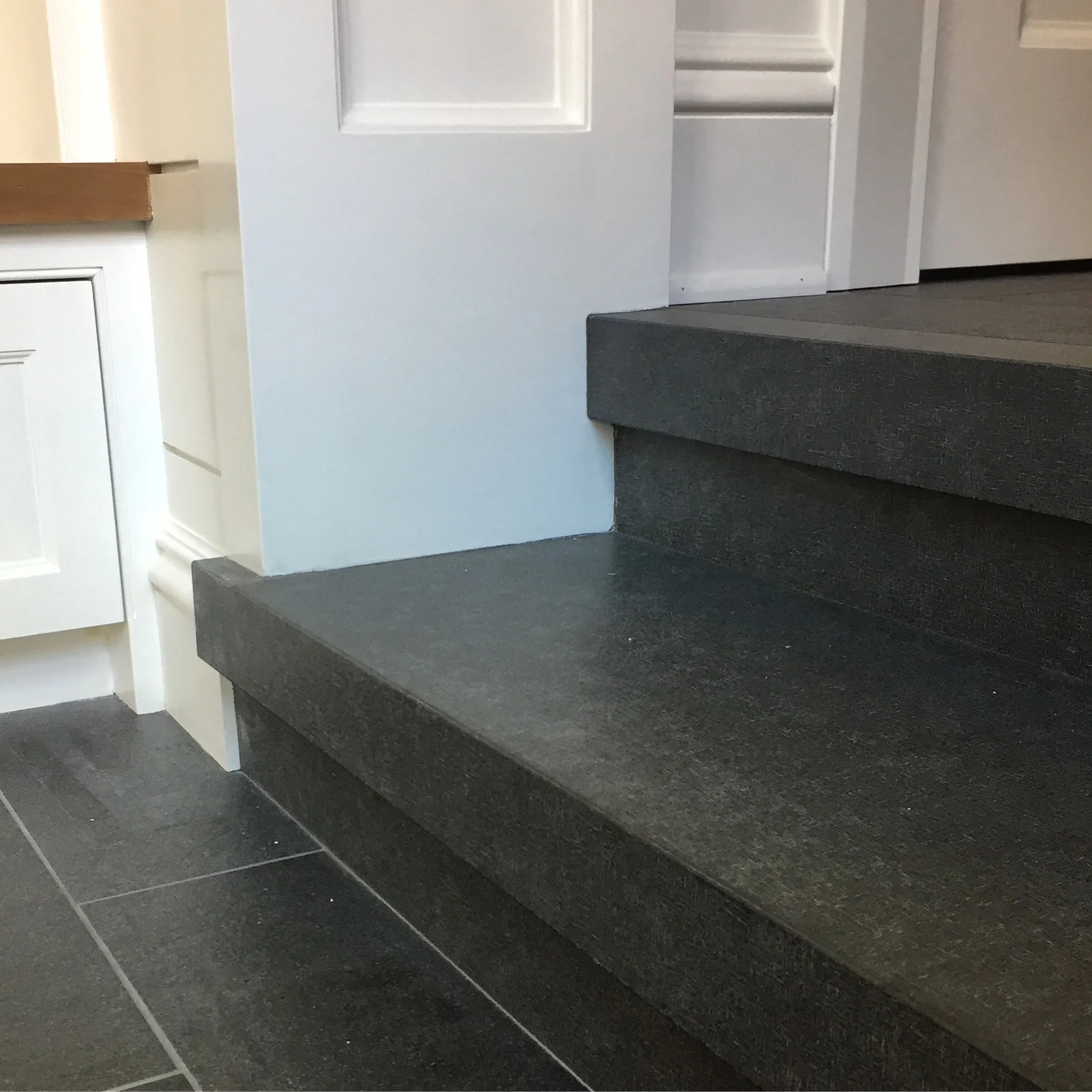 MUDROOM STEP DETAIL: Due to the height to grade and our inability to incorporate a stair down to grade on the exterior, the mudroom needed to have two steps. For the steps, we mitered together absolute black granite slabs with a bi-directional linen surface that matches, but slightly stands out from the absolute black granite floor tile which has a flamed and brushed surface.