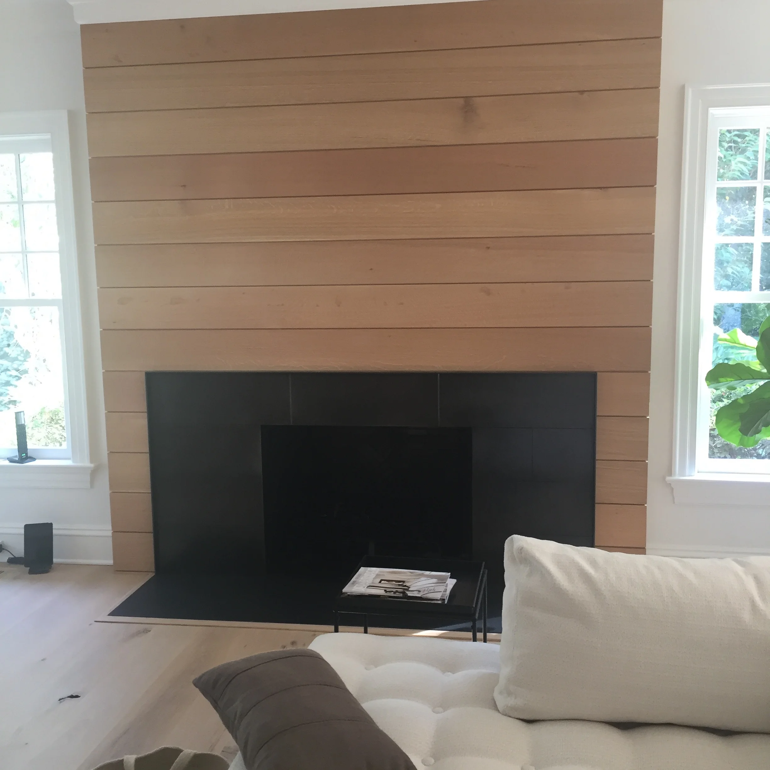 FAMILY ROOM FIREPLACE: An out-of-scale large traditional wood mantle and stone surround were demolished and replaced with a clean, white-oak ship lap wall treatment and a blackened steel surround. 