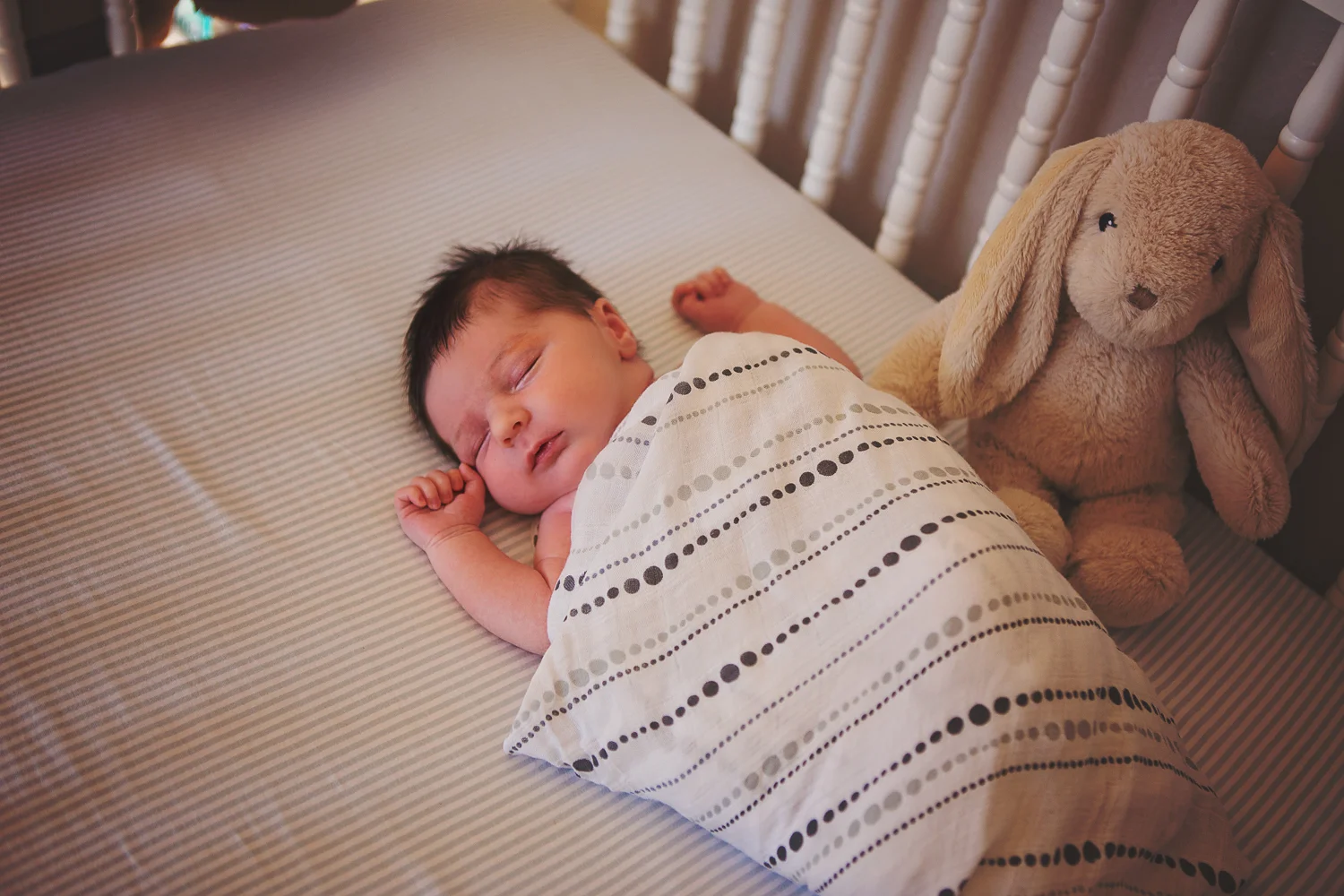 Newborn baby sleeps in crib for lifestyle session.