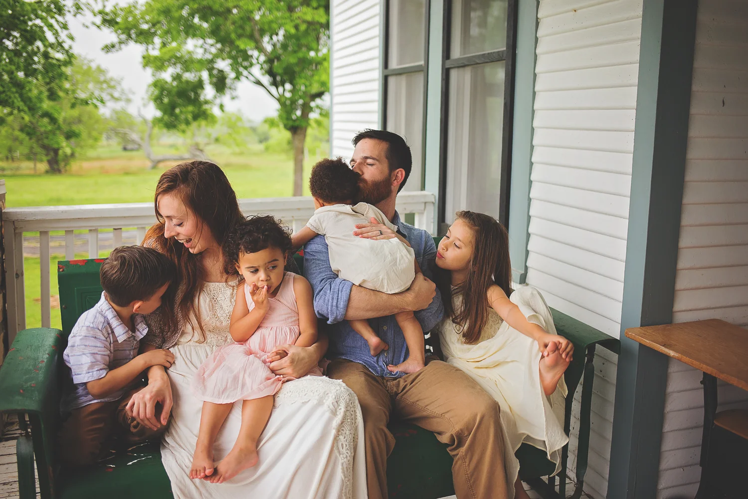Family all sits together on porch swing for Dallas-Fort Worth Texas family lifestyle session.