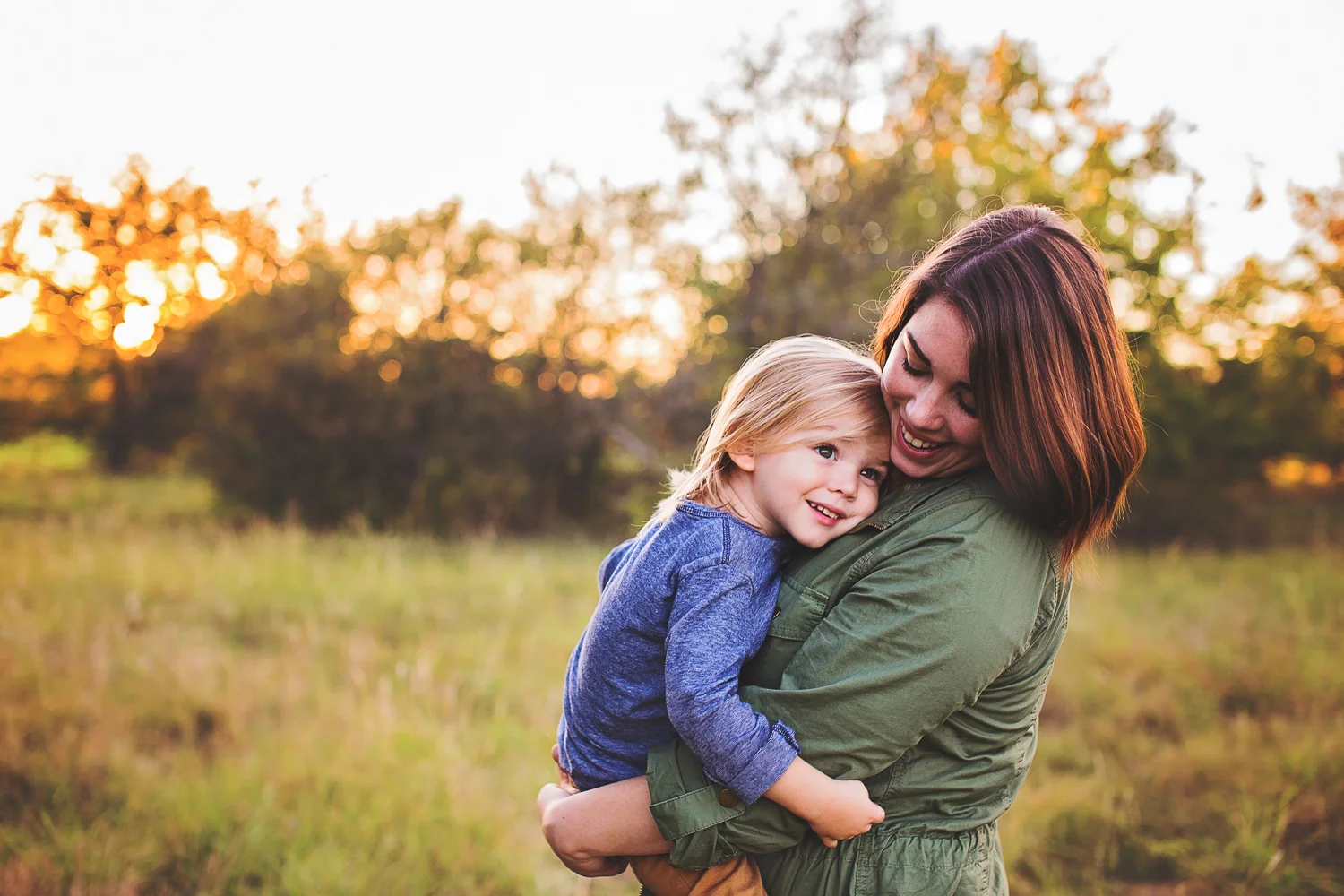 Beautiful mother and daughter portrait features mom smiling down at a happy little girl.