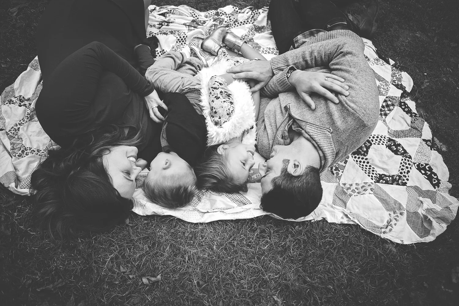 Stunning family portrait by Jessica Rene features family enjoying sweet conversation on blanket in field.