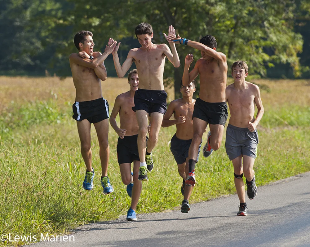 Evan Ehrenheim, center, receives high-fives from cross-country teammates Oscar Medina, left, and Juan Carrera, right, on Sept. 17 while jogging on Dogwood Drive in Carbondale, Ill.
