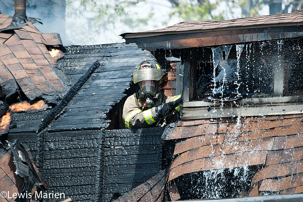 Carbondale Fire Department firefighter Ryan Hall works to put out the remains of a house fire at 208 W. Hospital Drive in Carbondale.