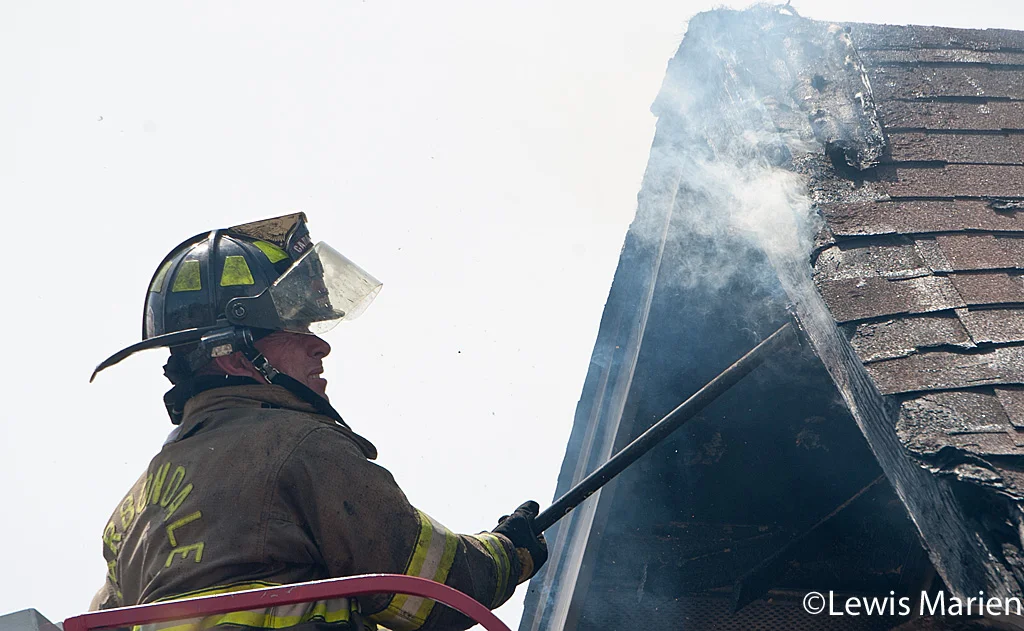 Carbondale Fire Department firefighter Bradley Lam checks for hotspots on the roof of 208 W. Hospital Drive in Carbondale.