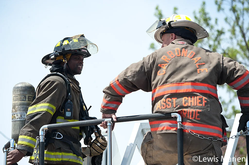 Carbondale Fire Department firefighter Wesley Clemmons (left) and Assistant Chief Stephen McBride talk after putting out a house fire at 208 W. Hospital Drive in Carbondale.