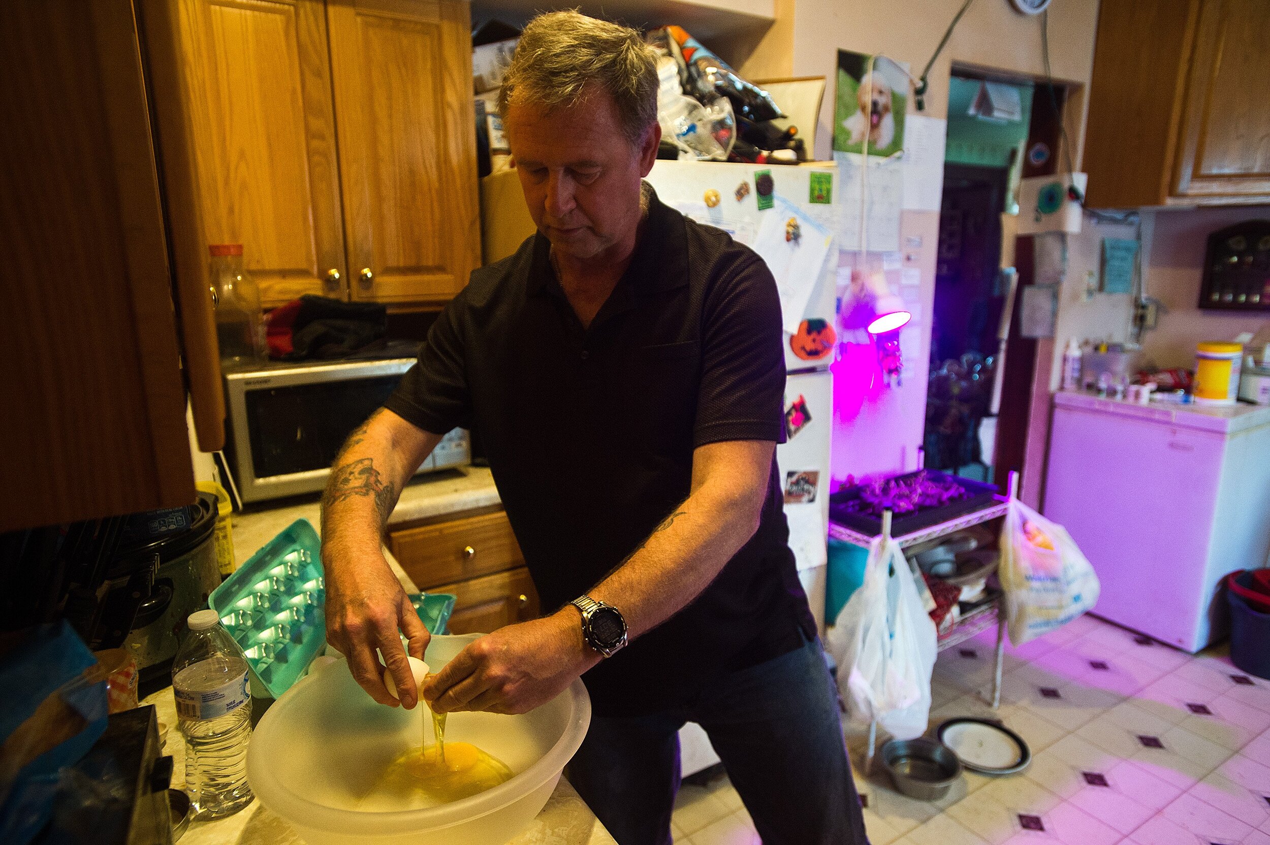  Dennis Fett breaks open eggs to bake dog treats on Tuesday, April 9, 2019, in the kitchen of his home in Roanoke, Illinois. Since undergoing deep brain stimulation surgery to ease his Parkinson's disease symptoms, Fett has been able to bake and cook
