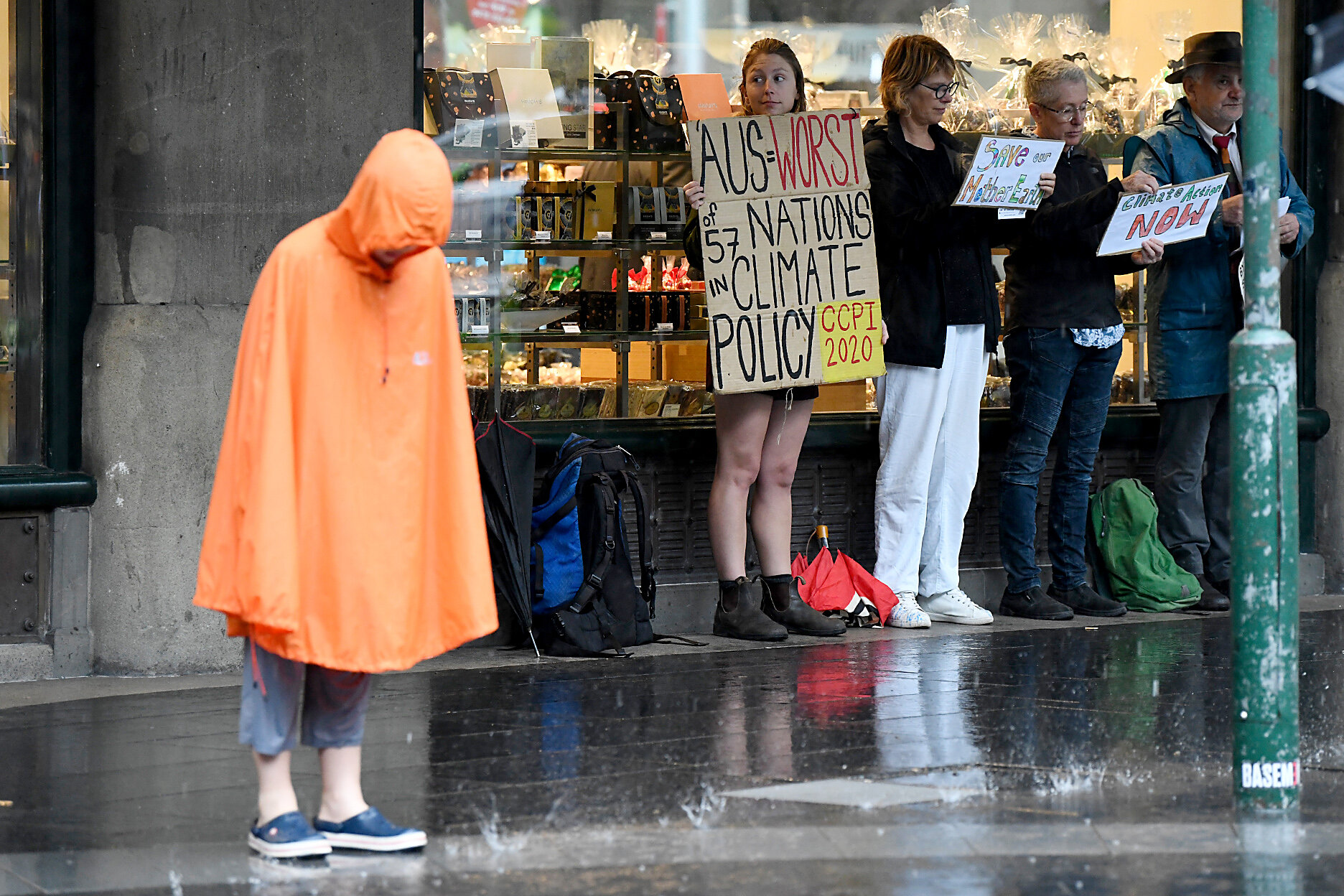  Climate change protestors are seen shielding themselves from the heavy rain in Sydney's CBD, Friday, January 17, 2020. Sydney is expected to receive 10-25 mms of rain today, while up to 50mm is forecasted for parts of NSW. (AAP Image) 