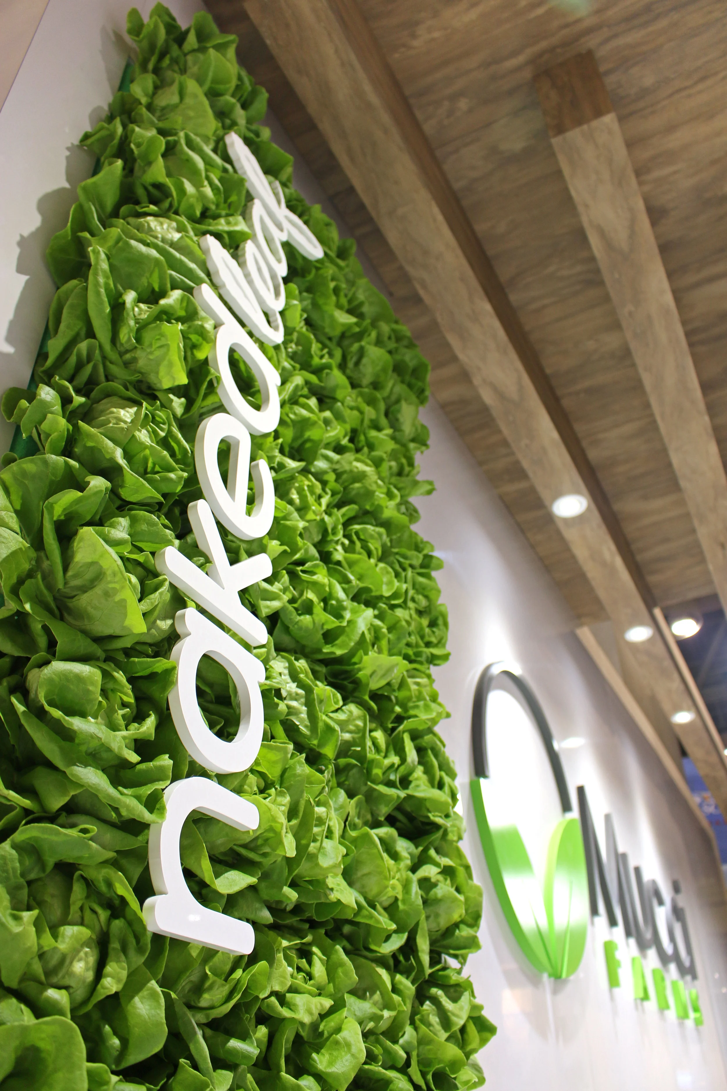 3-D LETTERING & LETTUCE WALL 16-foot-high towers provide the perfect backdrop for the use of dimensional lettering. Even at eye level the use of 3D logos is striking and contributes to the layers and depth of their design. We also integrated a custom wall featuring their ‘Naked Leaf’ living lettuce in water, with a painted acrylic logo nested within the leaves.