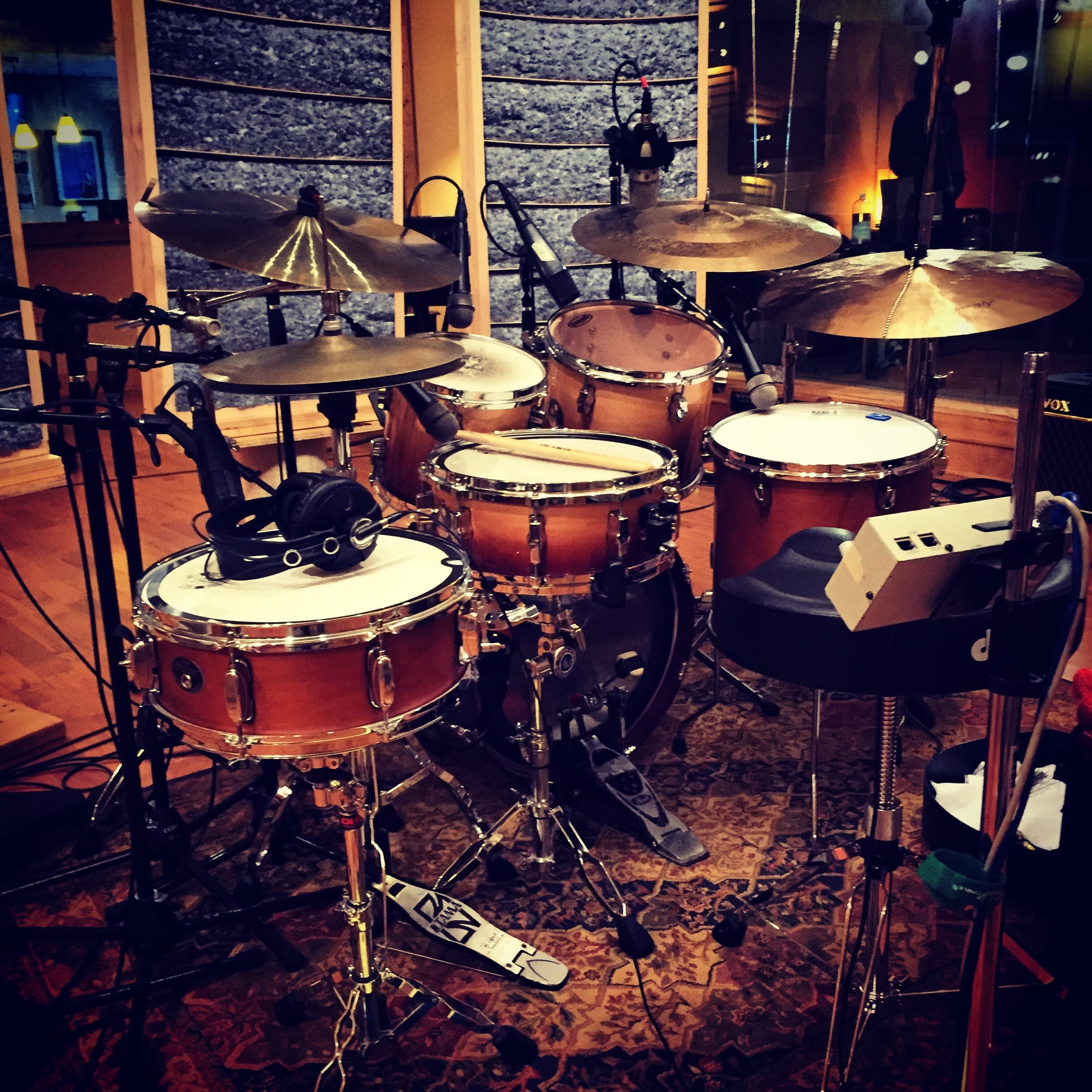 A recording studio with a drum set and microphones, surrounded by acoustic soundproofing panels.