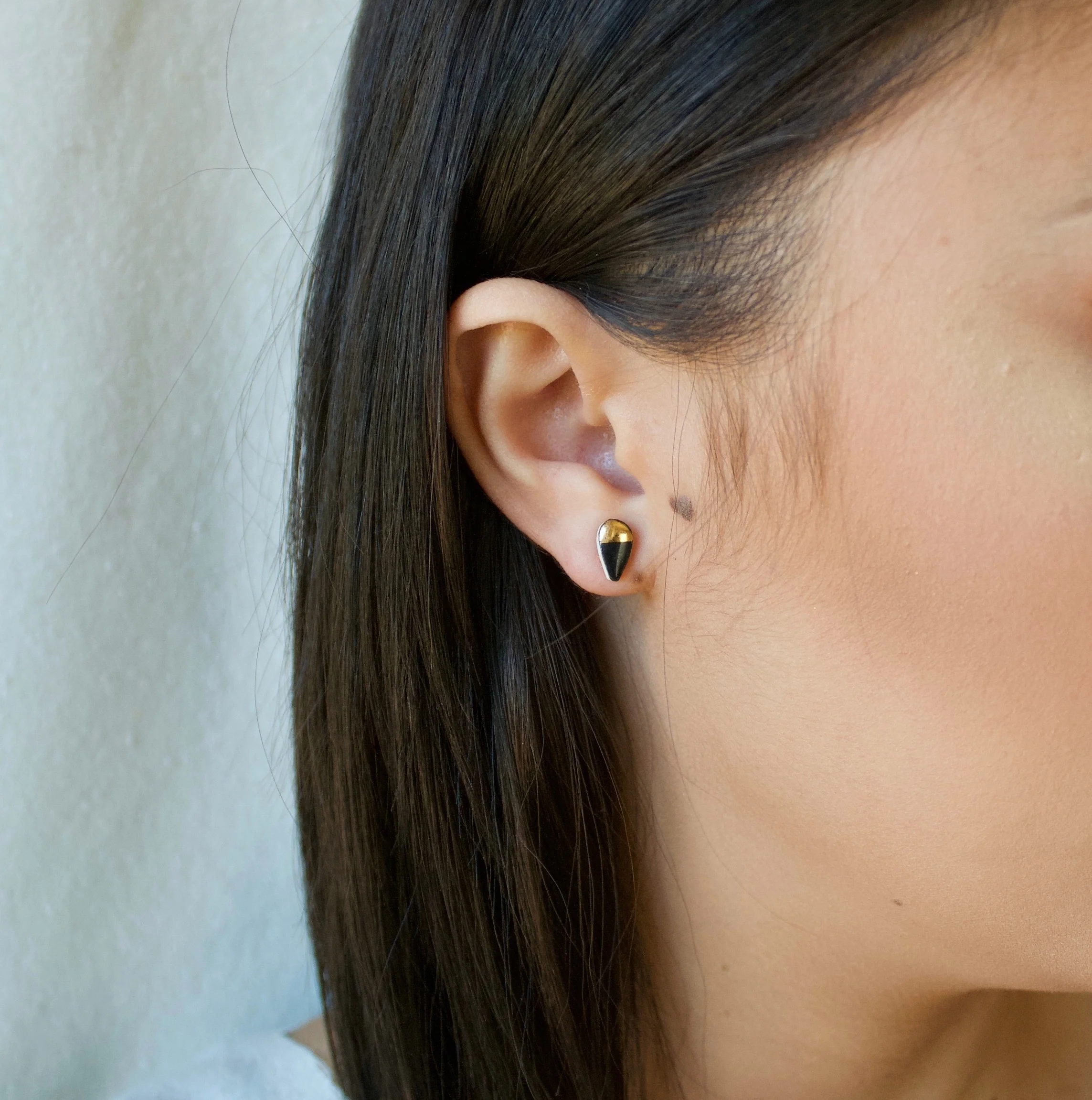 ZOË COMINGS model tiny petal studs black:gold half sl square.jpg