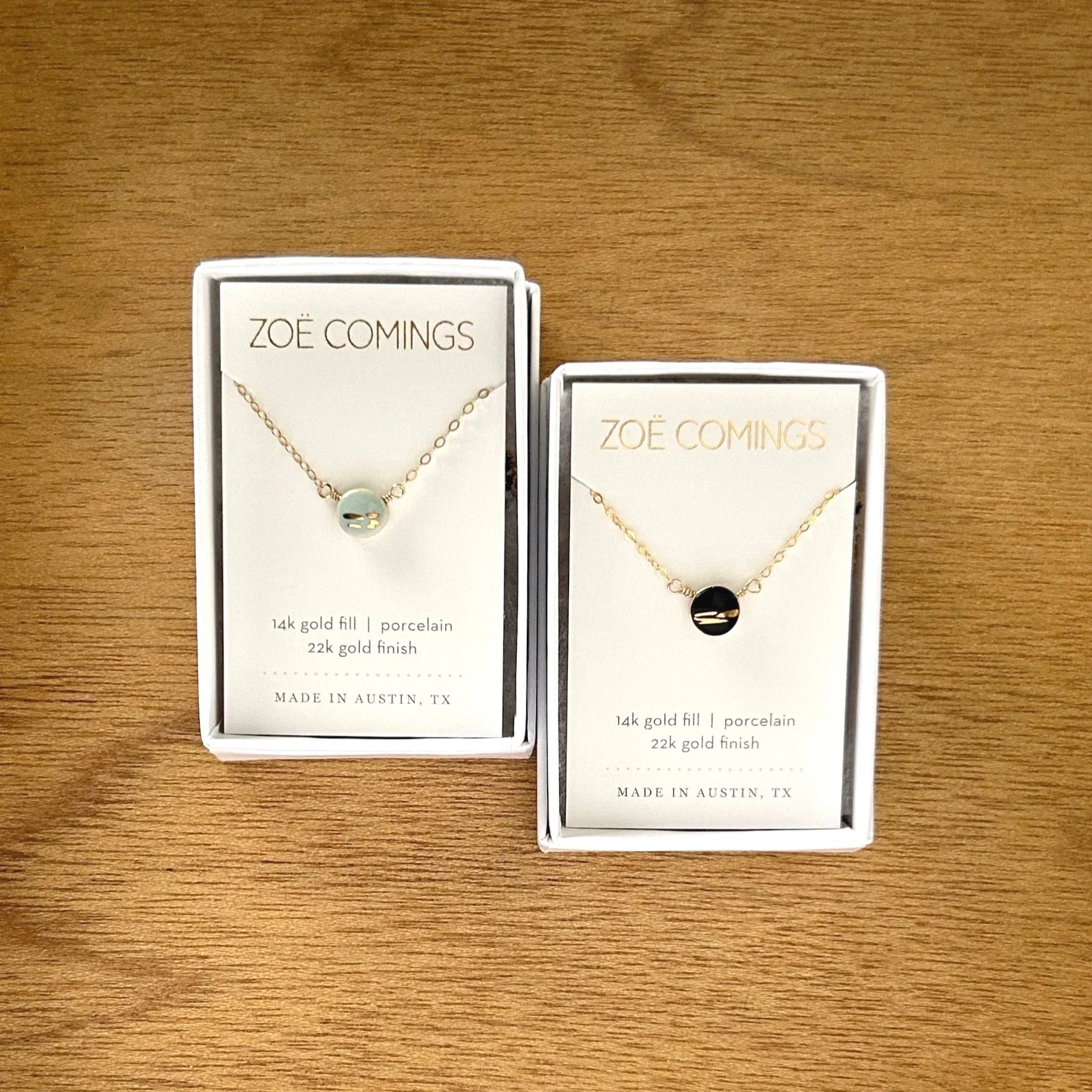 ZOE%CC%88+COMINGS+teeny+pebble+necklace+bl+%2B+bk%3Agold+stripe+boxed+wdbkg.jpg