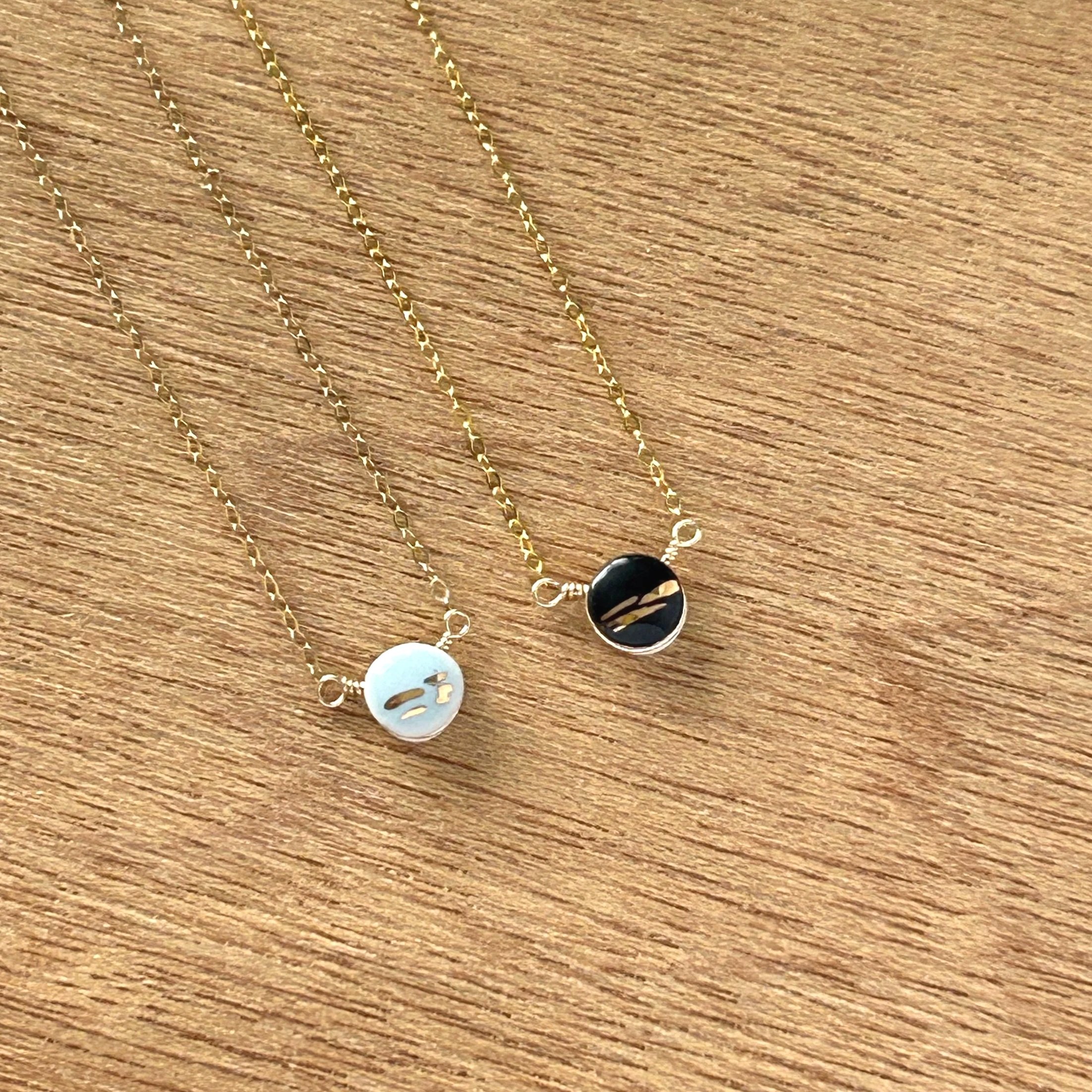 ZOE%CC%88+COMINGS+teeny+pebble+necklace+bl+%2B+bk%3Agold+stripe+wdbkg+a.jpg