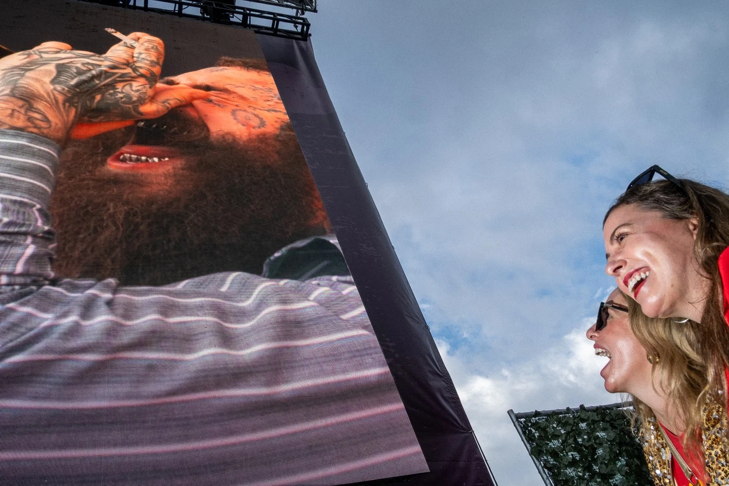 Post Malone performs at a VIP party before the Super Bowl in New Orleans, with his face shown on a large screen and fans cheering in the crowd.
