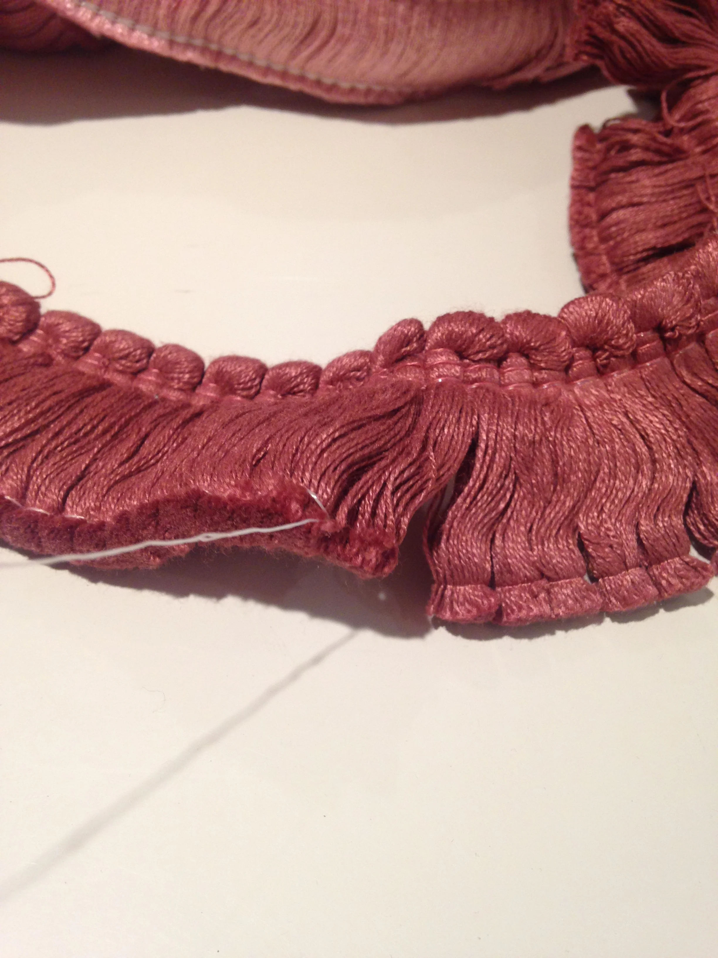 First step - pull the thin piece of thread holding the bottom of the trim together. It should pull away easily.