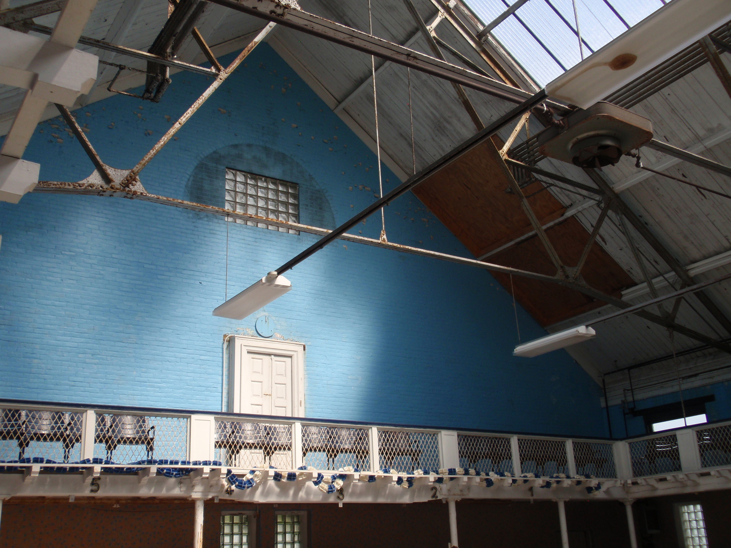  The western end of the pool. A large semi-circle window had been here, but was replaced with glass blocks in the 1970s. The door provides access to an outdoor catwalk that was over the original outdoor pool. 